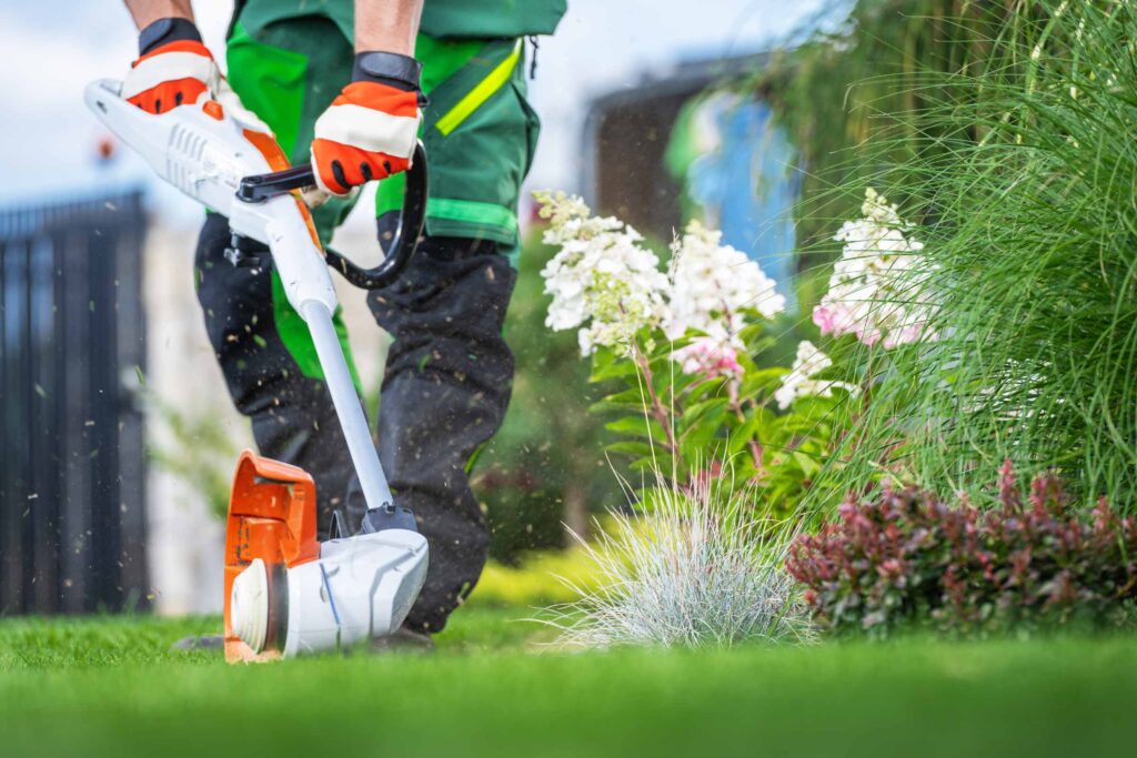 Man in professional lawn care outfit trimming a lawn edge with a string trimmer in Savannah Georgia